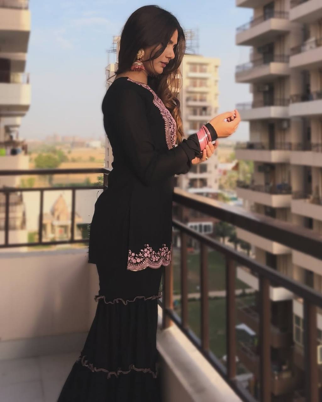 Contemporary black sharara set for women, with a heavily embroidered kurta, unique ruffled tiered sharara, and a matching sheer dupatta.