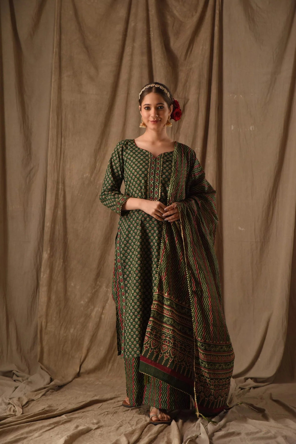 Woman wearing a dark green cotton anarkali set with intricate block prints, featuring a flared kurta and matching dupatta.