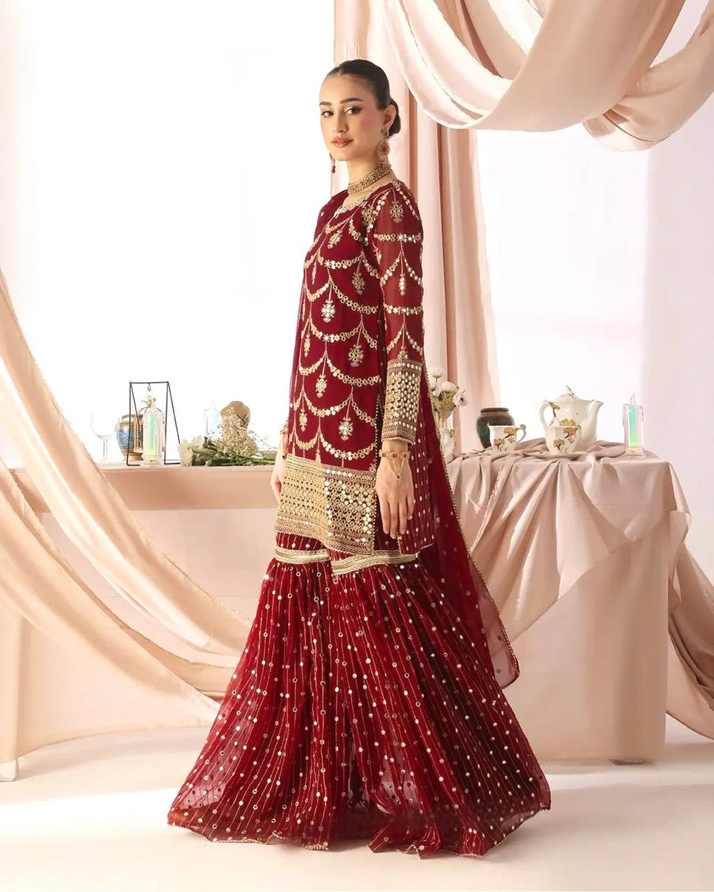 Designer burgundy red party wear gharara set for women, featuring a heavily embellished kurta with mirror work and a voluminous tiered sharara.