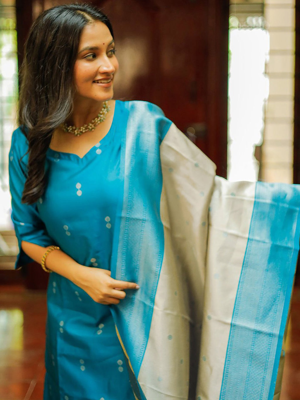 Designer turquoise blue silk blend suit with subtle tonal motifs, paired with a luxurious contrast Banarasi dupatta, ideal for wedding guests and festive occasions.