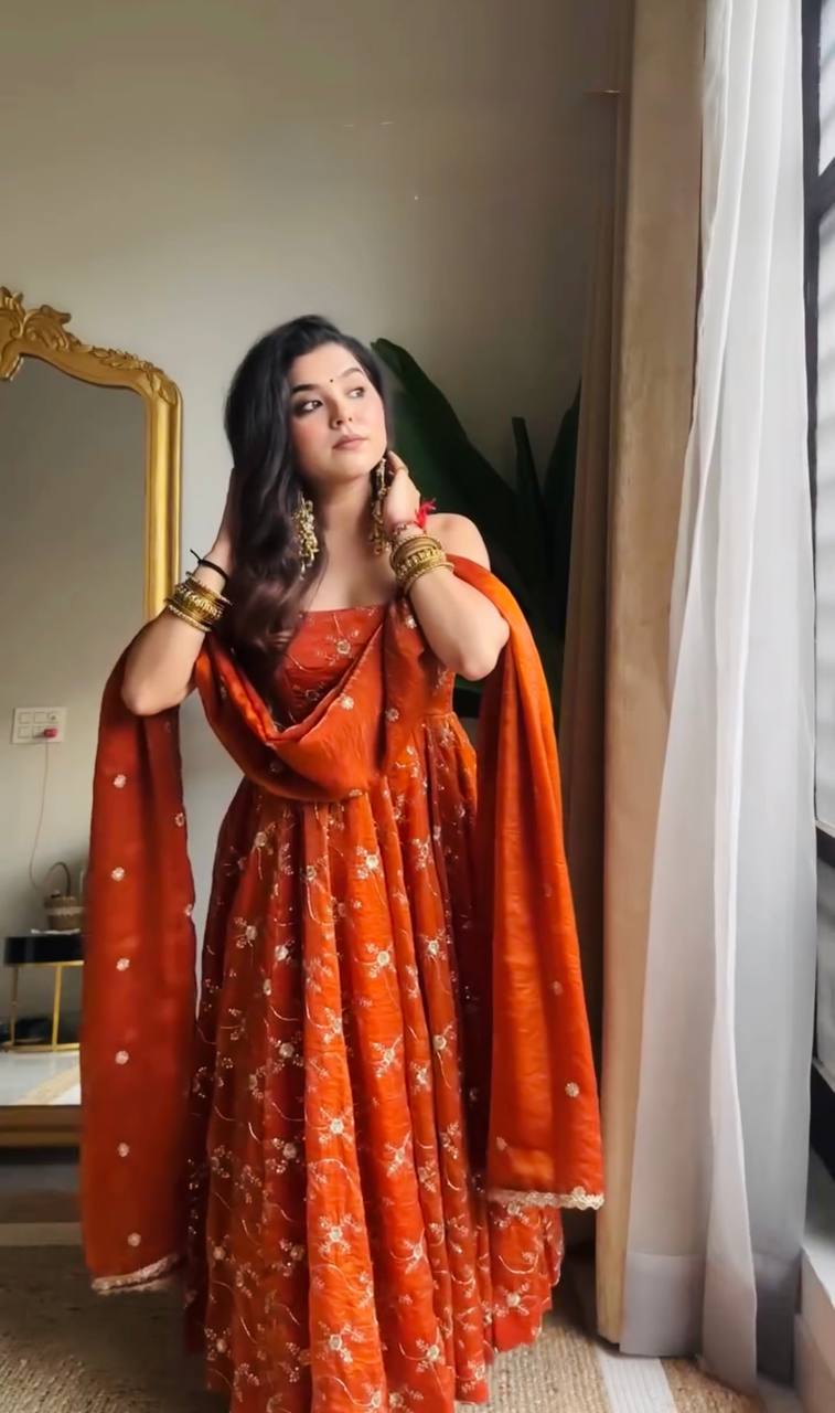 Elegant burnt orange ethnic gown with all-over gold print/embroidery, a magnificent flare, and a coordinating dupatta, exuding traditional charm.