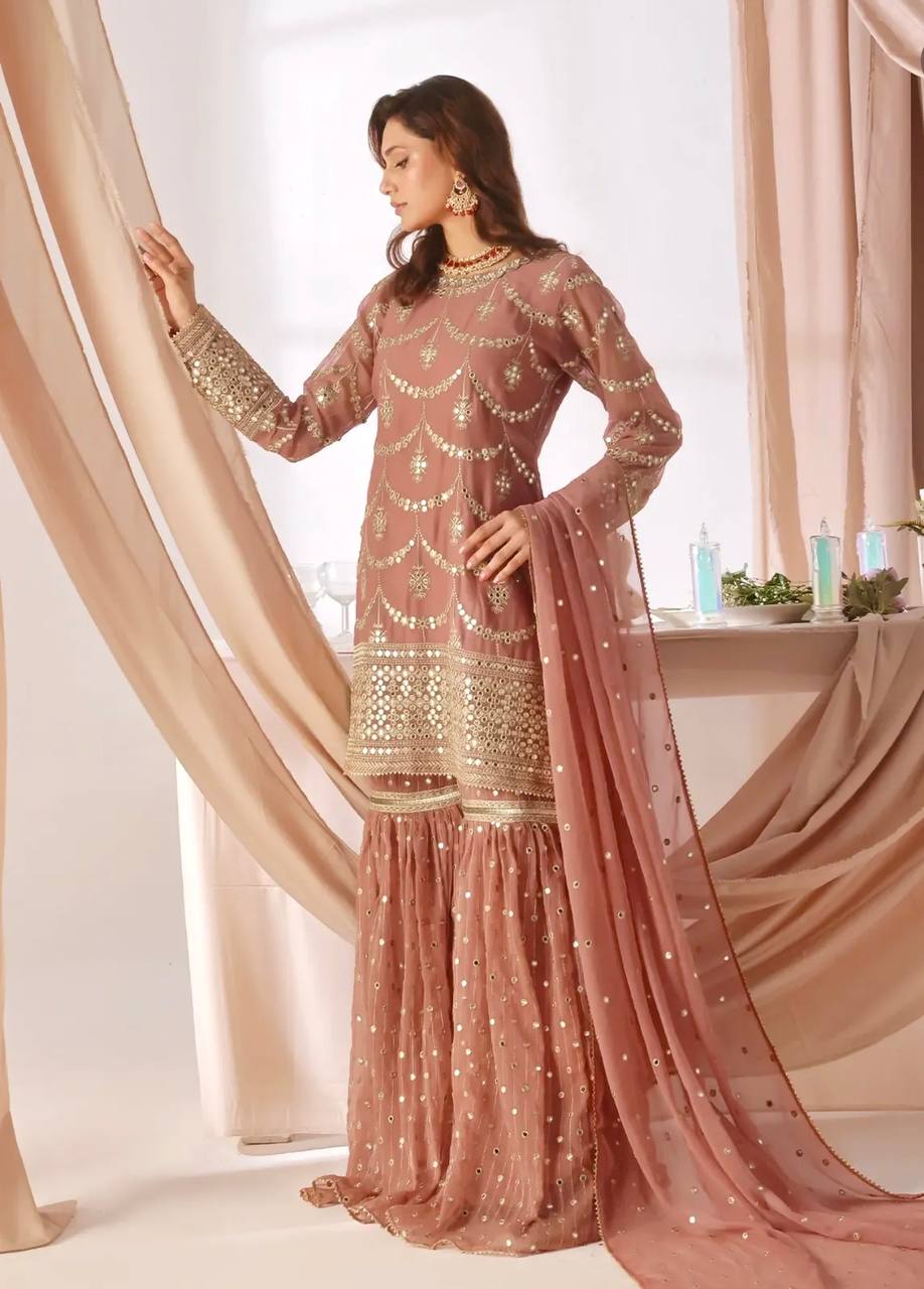 legant rose gold ethnic wear featuring a mid-length kurta with intricate gold embellishments and a matching tiered sharara, perfect for special occasions.