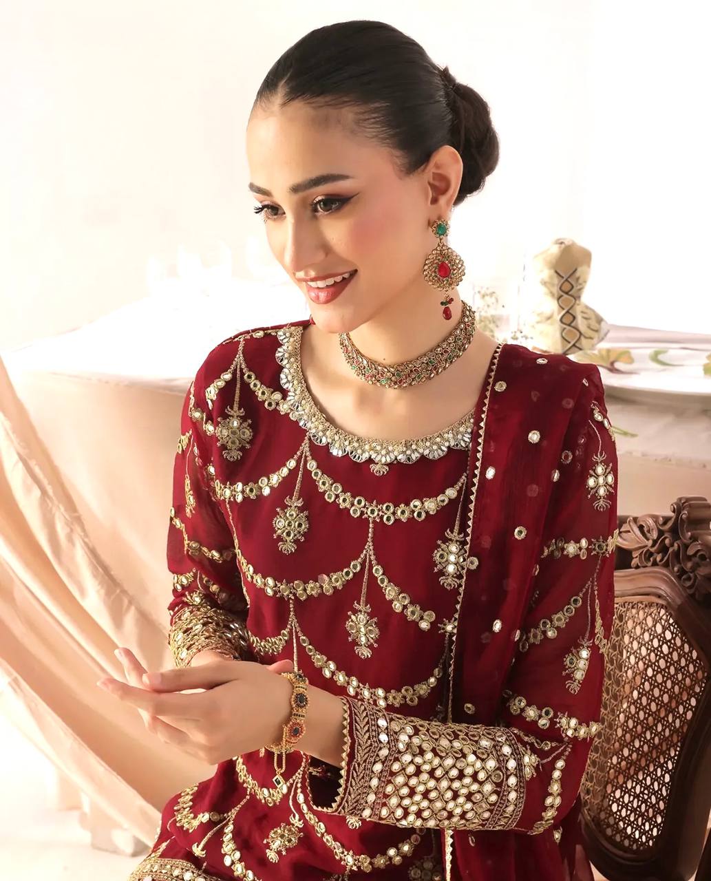 Elegant wine red ethnic wear featuring a mid-length kurta with intricate gold embellishments and a matching tiered sharara, perfect for special occasions.