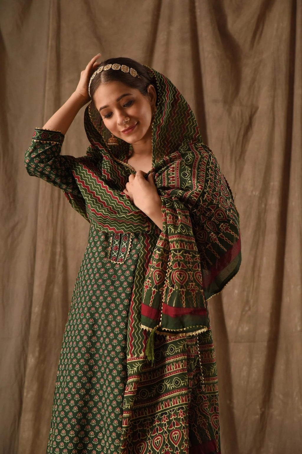 Model in a festive dark green cotton anarkali with rich prints, suitable for traditional events.