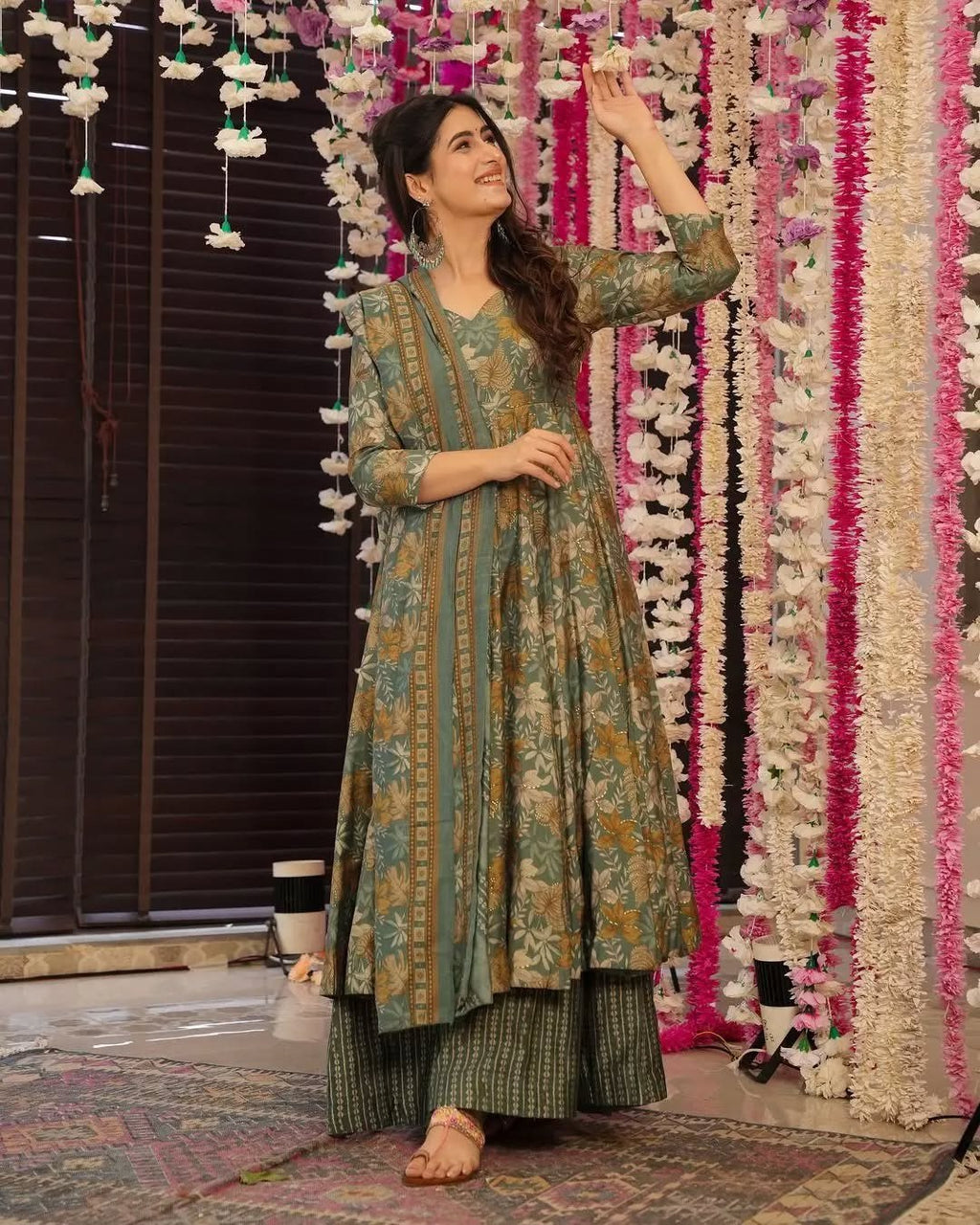 Model in a festive sage green printed anarkali dress with beautiful floral motifs, perfect for celebrations.
