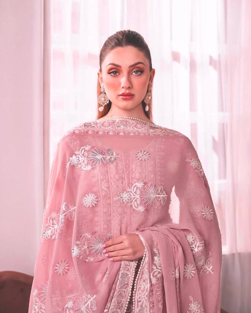 Model in a festive light pink Chikankari style embroidered kurta set with broad palazzo pants and a matching dupatta, ideal for daytime events.