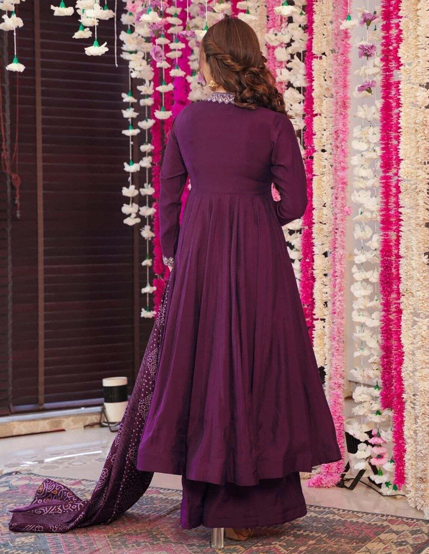Model in a festive plum anarkali dress with subtle embroidery on the neckline, matched with a vibrant tie-dye Bandhani dupatta.
