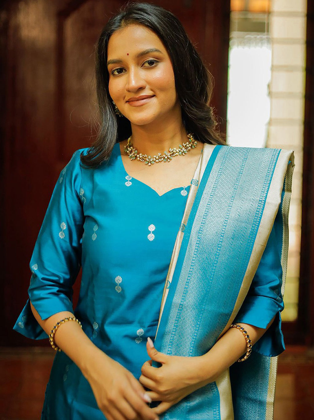 Lalily.in festive teal blue kurta set with straight pants and a cream Kanjivaram style dupatta featuring heavy gold and blue weaving, perfect for celebrations.