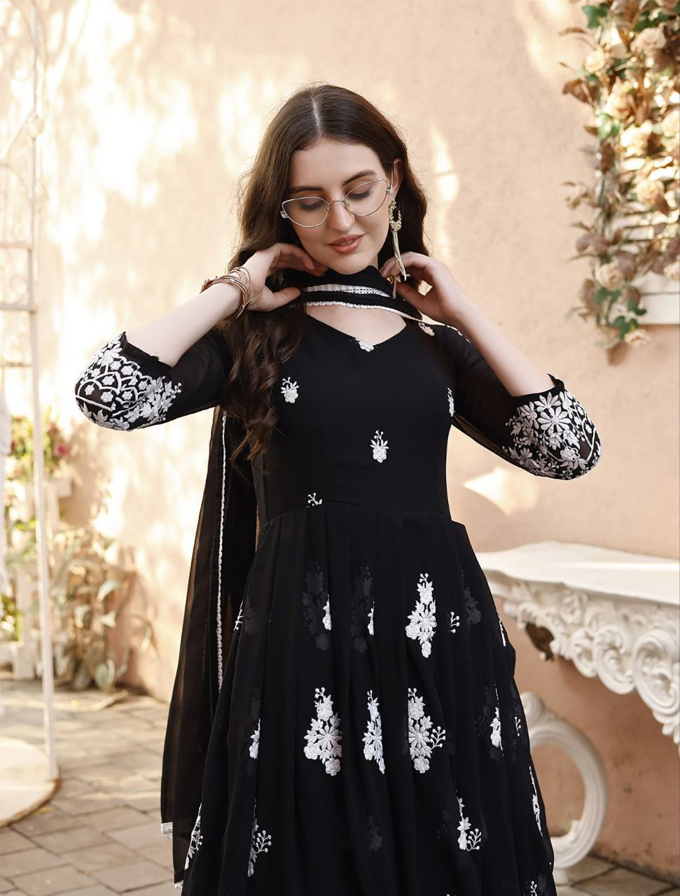 Model posing in a gorgeous black anarkali gown with extensive white thread work, ideal for festive wear.