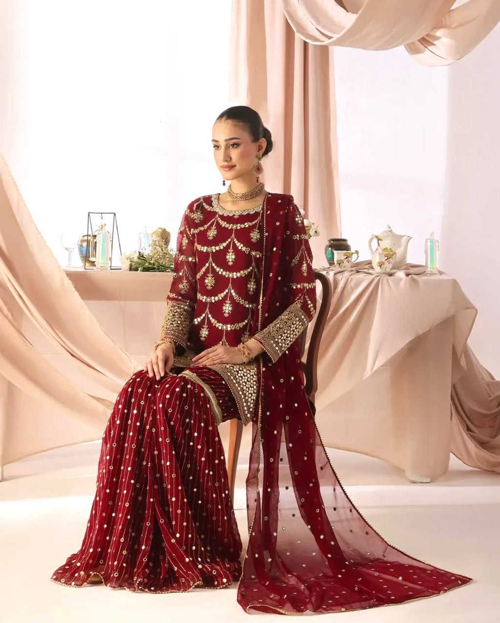 Glamorous cherry red sharara set for women, with a heavily embroidered kurta, tiered sharara, and a matching sheer organza dupatta with gold borders.