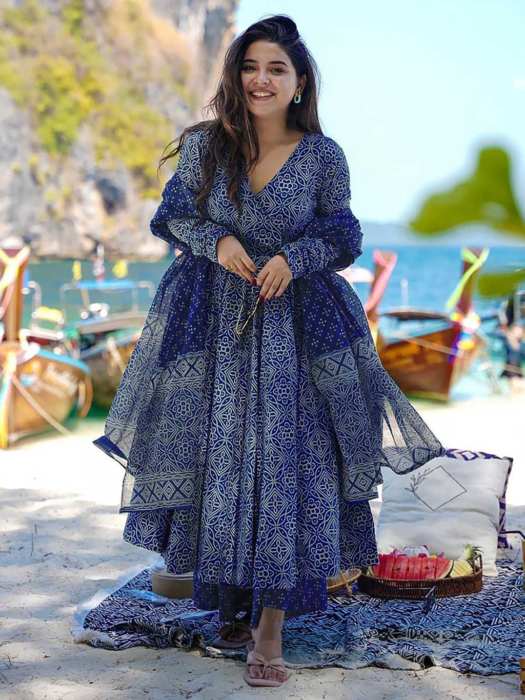 oman wearing an indigo blue cotton printed anarkali kurta with full sleeves, paired with matching printed palazzo pants and a coordinating dupatta, on a beach setting.