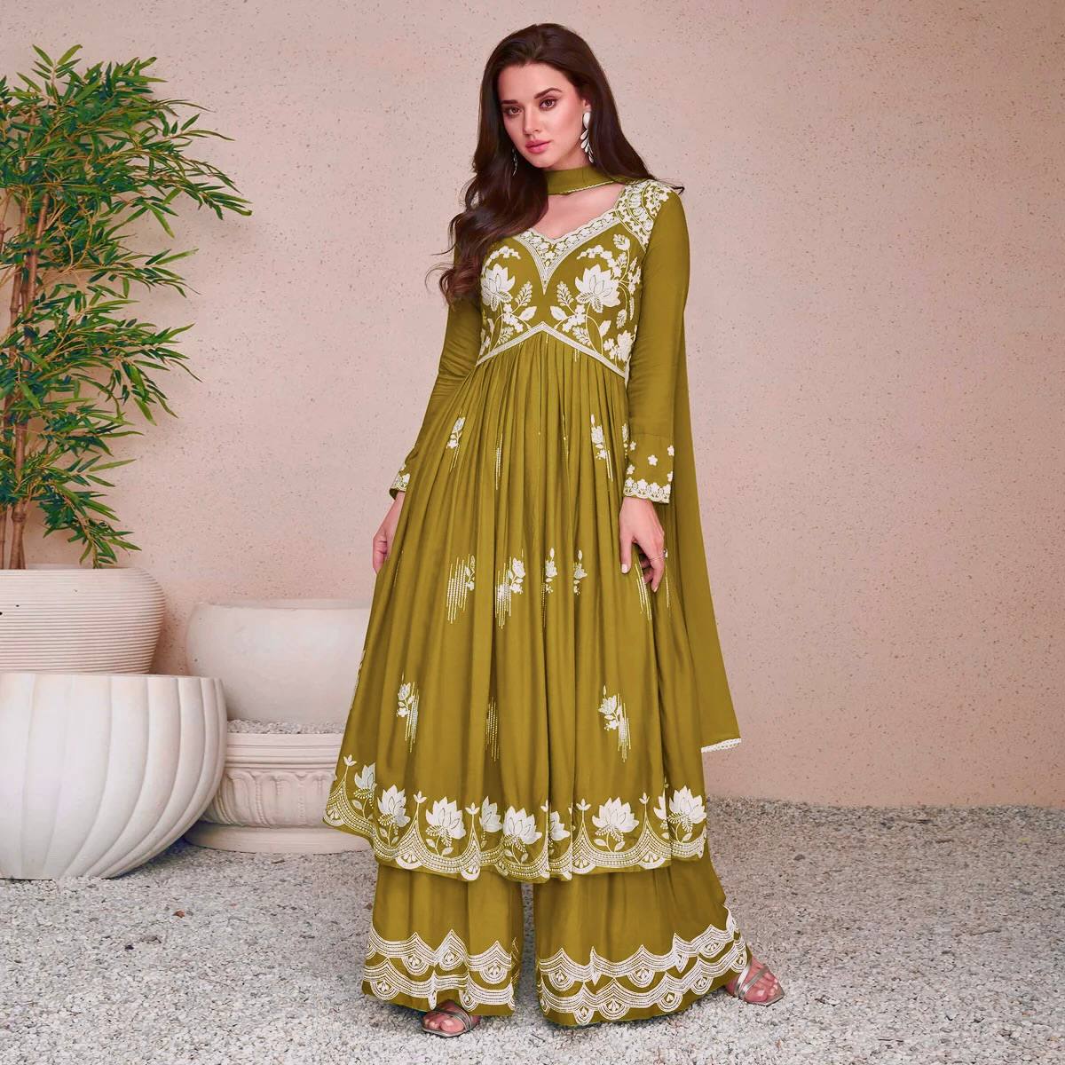 Woman wearing an olive green georgette flared anarkali kurta with intricate white thread floral embroidery on the yoke and hem, paired with matching embroidered palazzo pants and a dupatta.