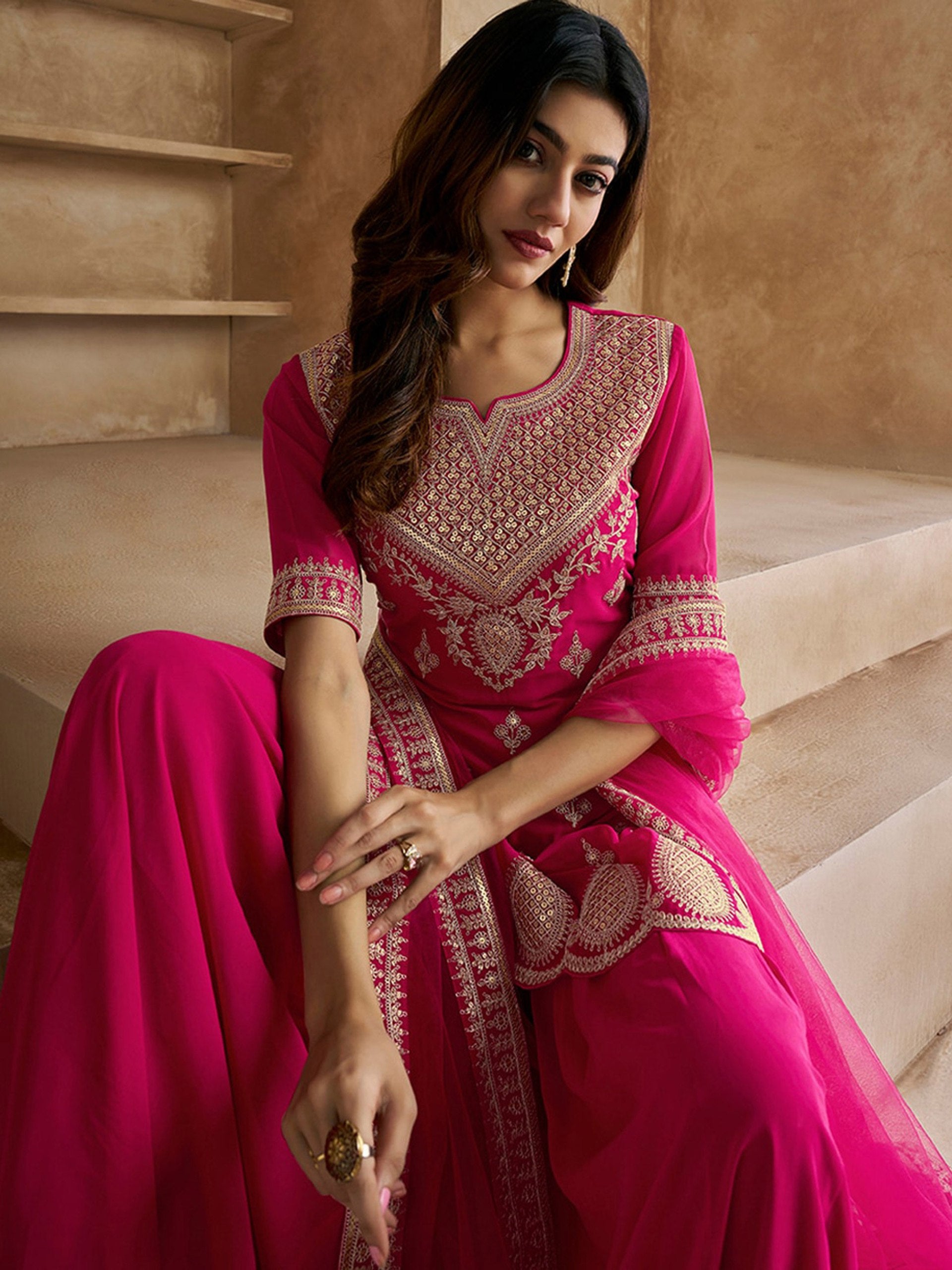 Party wear magenta sharara suit with intricate embroidery on the V-neck kurta and a richly flared sharara, ideal for special occasions.