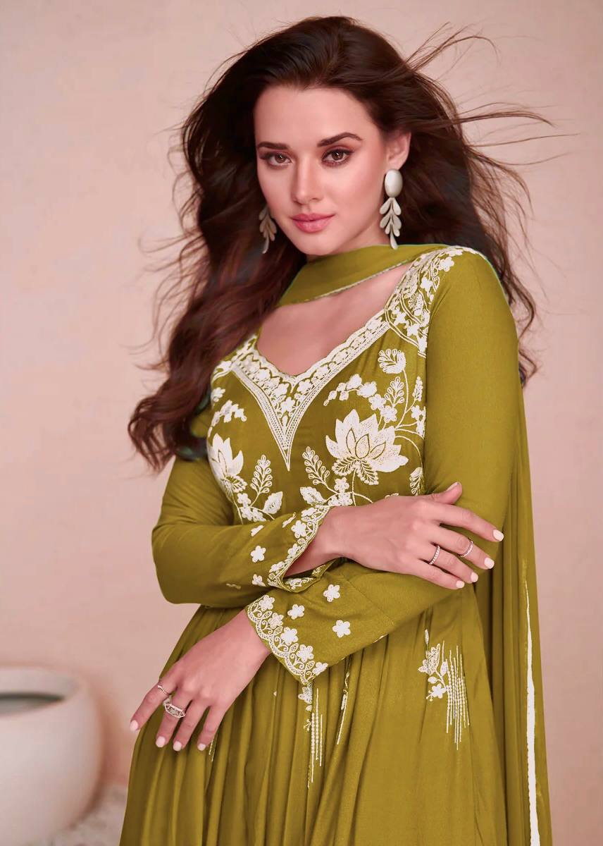 Model in a party wear olive green Chikankari style embroidered Anarkali suit with palazzo pants and a dupatta, ideal for elegant gatherings.

