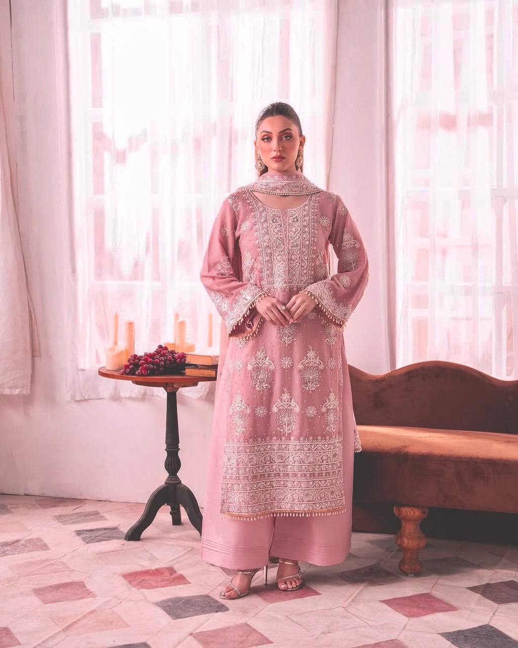 Woman wearing a pastel pink straight-cut kurta with intricate white thread embroidery, bell sleeves, broad palazzo pants, and a matching dupatta.