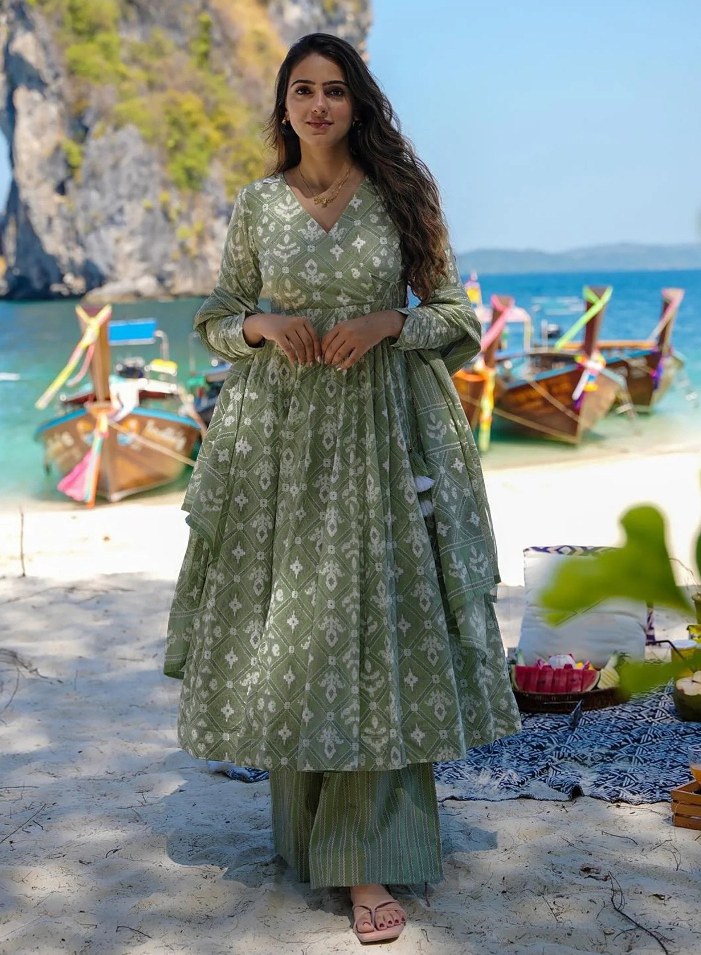 Model in a resort wear sage green anarkali with abstract white print, striped palazzo pants, and a dupatta, perfect for beach holidays.