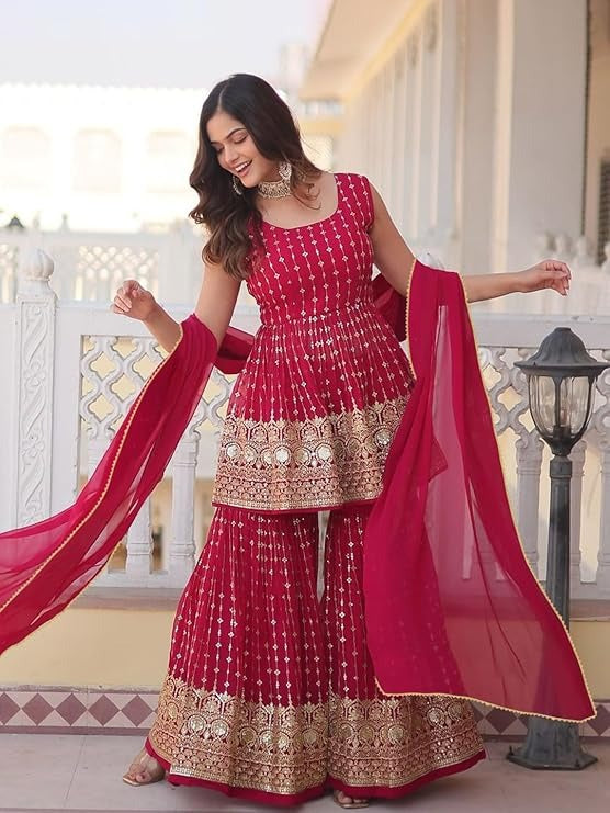 Traditional hot pink peplum top with gold mirror work, matched with heavily embroidered flared sharara pants and a coordinating dupatta.
