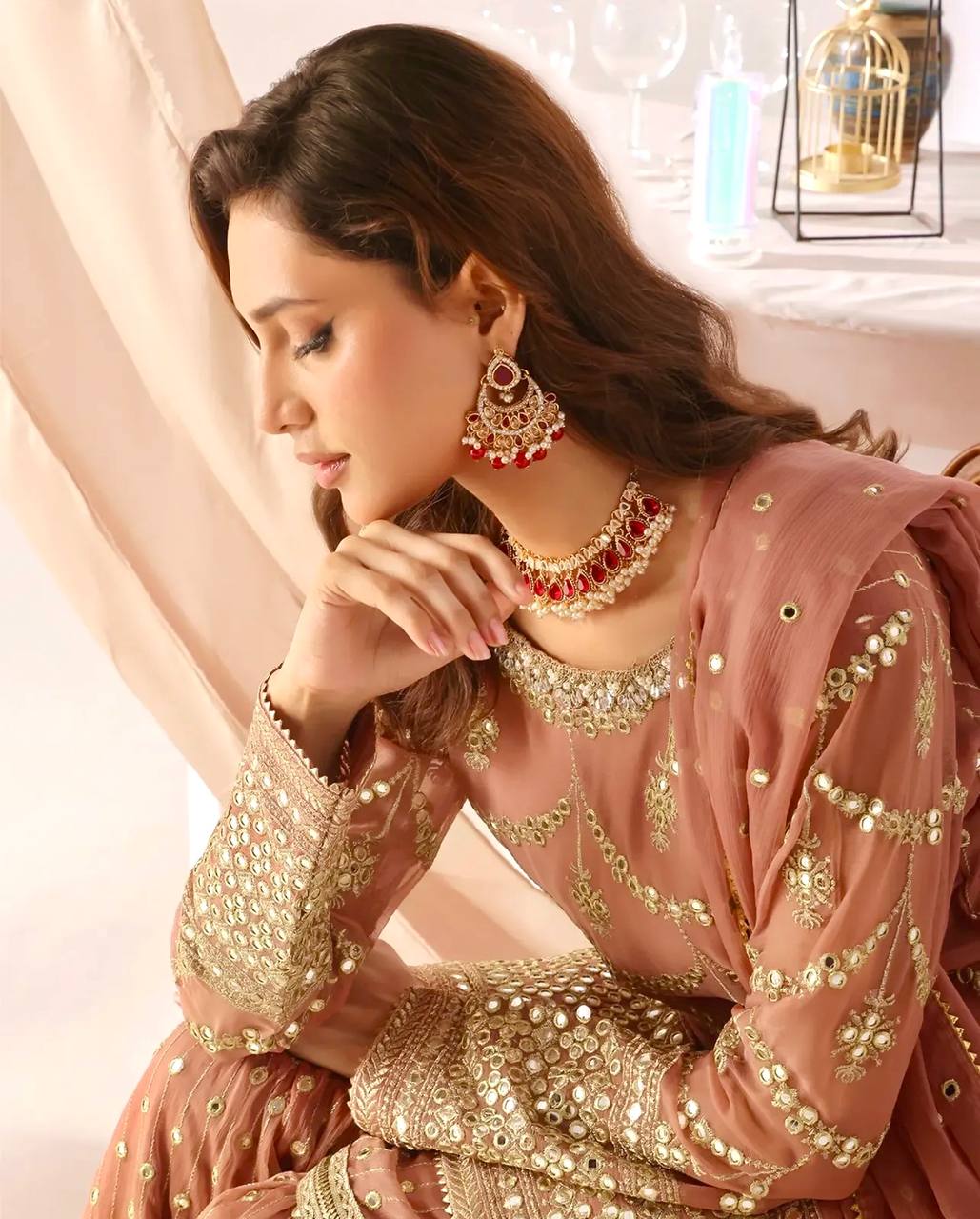 Model in a wedding guest pink sharara suit with full sleeves, intricate gold sequin embroidery on the kurta, and a tiered sharara with scattered sequins.