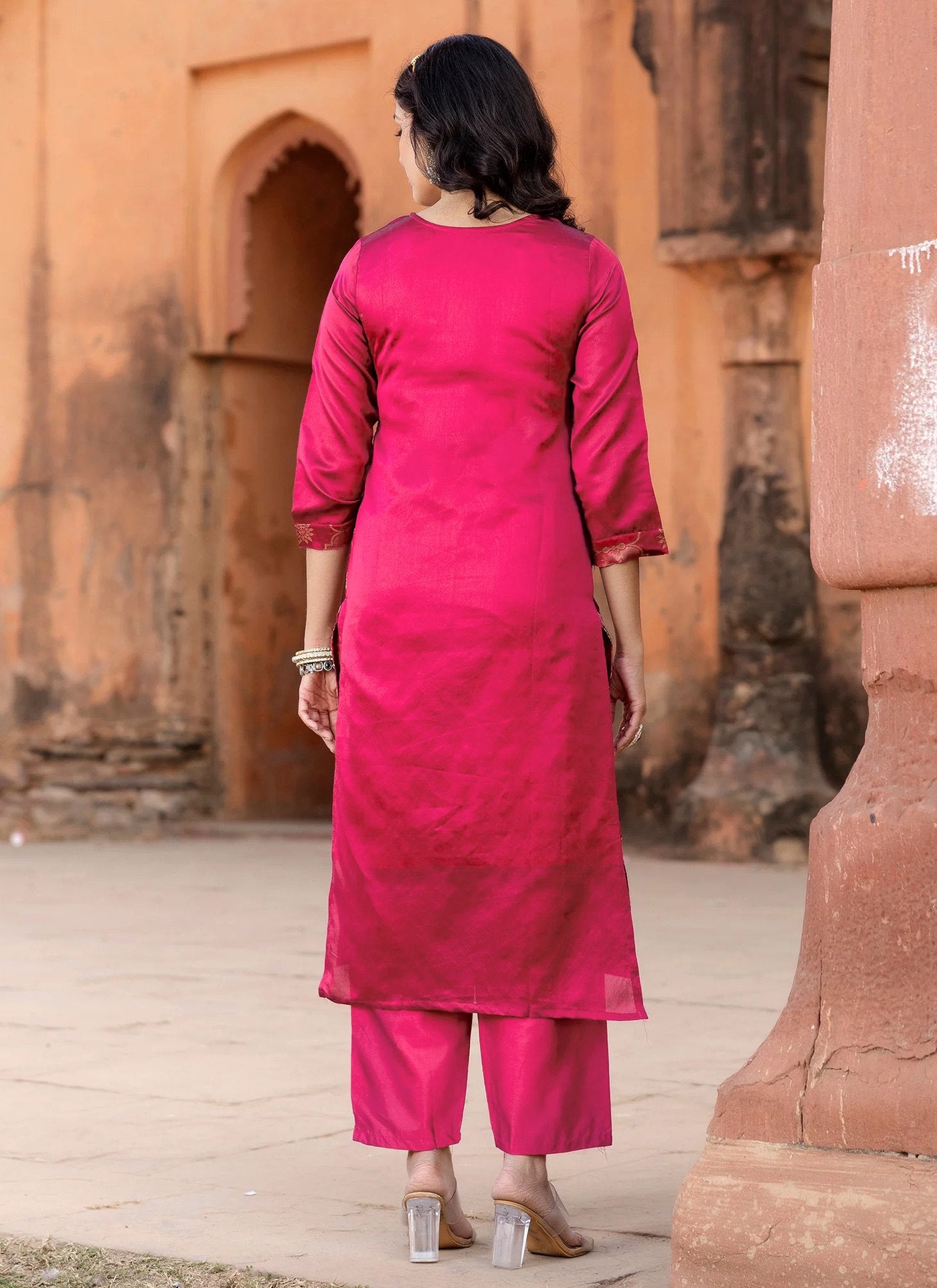 Model in a wedding and party wear rani pink brocade kurta set, featuring rich gold motifs on a silk blend fabric.